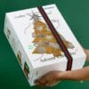 Korres Beauty Adventskalender 2026, Box mit grün-rotem Band in den Händen gehalten