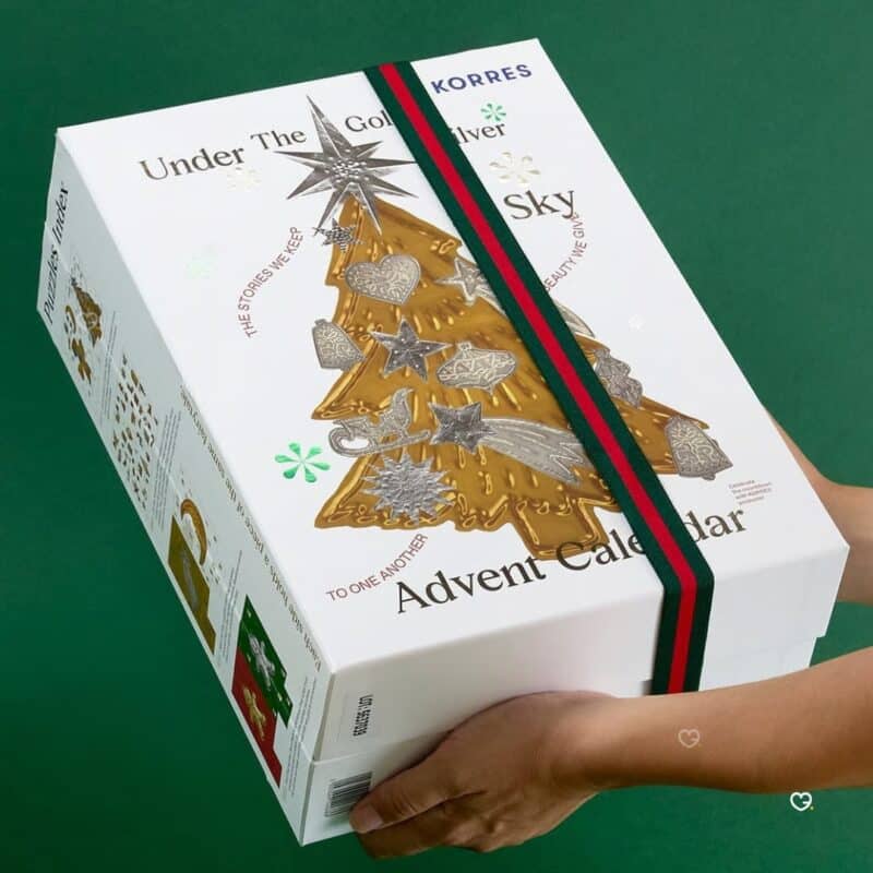 Korres Beauty Adventskalender 2026, Box mit grün-rotem Band in den Händen gehalten