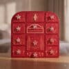 Charlotte Tilbury Adventskalender 2026, rote Beauty-Box mit 12 Türchen auf einem Holztisch