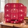 Charlotte Tilbury Adventskalender 2026 auf einer Holzkommode, ein Türchen geöffnet, daneben Lippenstift und Puderdose