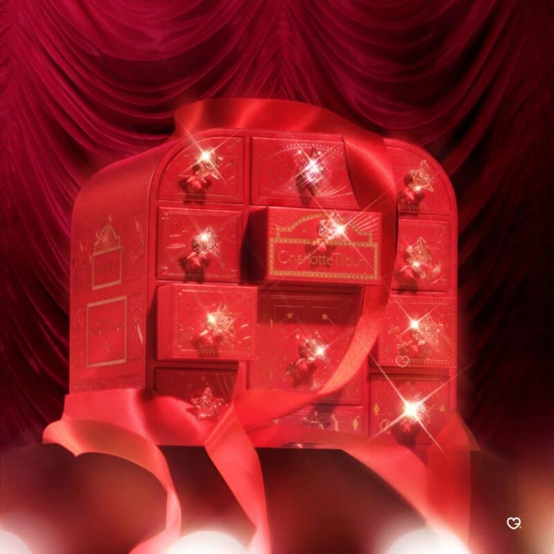 Charlotte Tilbury Adventskalender 2026 geschlossen mit roter Schleife vor Bühnenvorhang