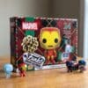 Funko Pocket POP Marvel Adventskalender 2026, Verpackung mit vier Figuren davor: Spider-Man Frost, Iron Man, Black Panther und Schneemann-Captain-America