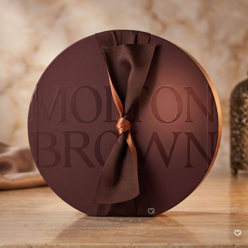 Molton Brown Adventskalender 2026 geschlossene Box auf goldenem Marmor mit Laterne