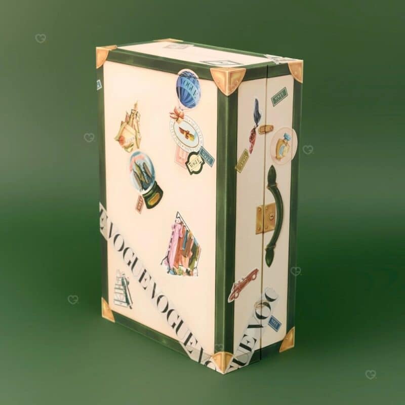 Vogue Adventskalender 2026, geschlossene Reisetruhe vor tannengrünem Hintergrund, Luxus Adventskalender