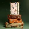 Vogue Adventskalender 2026 Reisetruhe auf einem Stapel Vintage-Koffer, Beauty Adventskalender