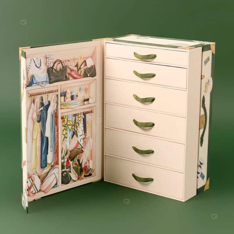 Vogue Adventskalender 2026, geöffnete Reisetruhe mit 25 Schubladen und illustrierter Garderobe