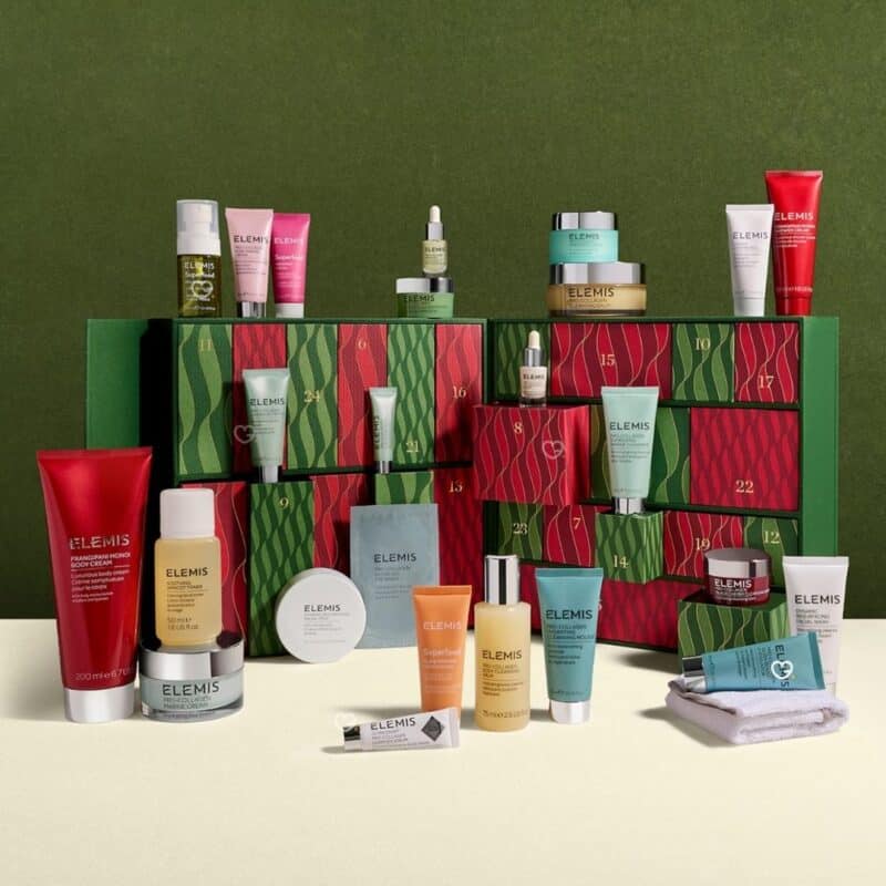 Geöffneter Elemis Luxus-Adventskalender 2026 mit sichtbaren Produkten auf grünem Hintergrund