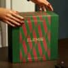 Hände halten die geschlossene Elemis Adventskalender-Box 2026, festliche Atmosphäre