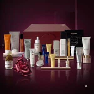 Die 26 Produkte des Niche-Beauty Adventskalender 2026 vor der burgunderroten Box