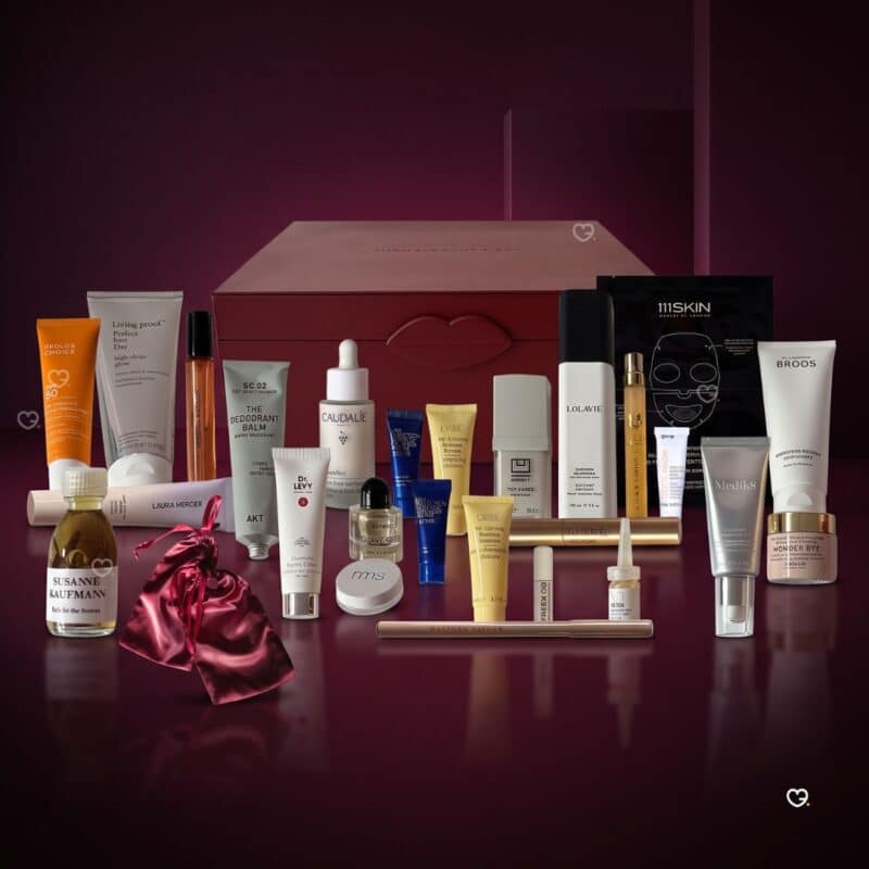 Die 26 Produkte des Niche-Beauty Adventskalender 2026 vor der burgunderroten Box