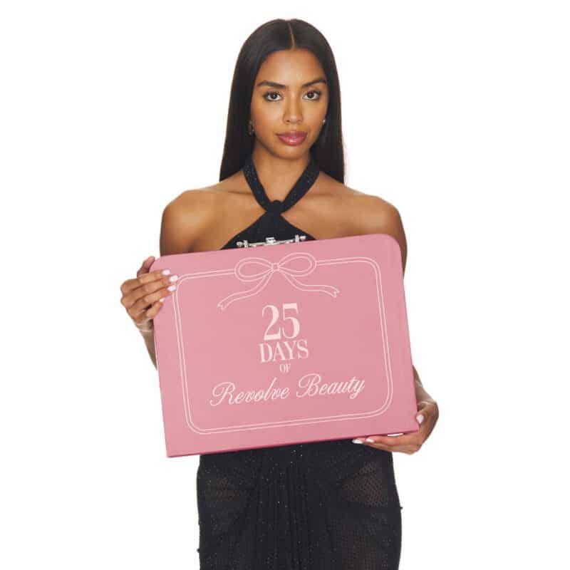 Model hält den rosa Revolve Beauty-Koffer, Variante mit 12 Türchen