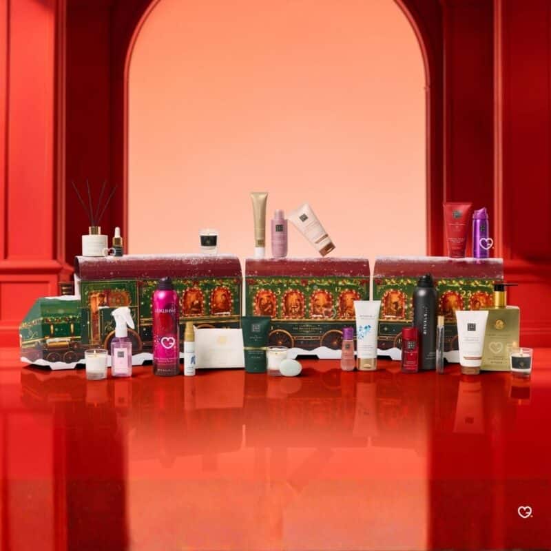 Alle 24 Produkte des Rituals Premium Adventskalender 2026 vor dem geöffneten Zug