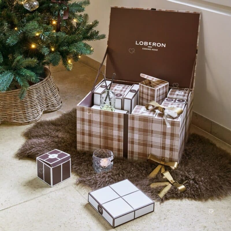 Loberon Adventskalender 2026 geöffnet auf einem Fellteppich unter dem Weihnachtsbaum