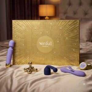 Sinful Premium Adventskalender 2026 im Schlafzimmer mit Wand-Vibrator, Rabbit und Massagekerze.